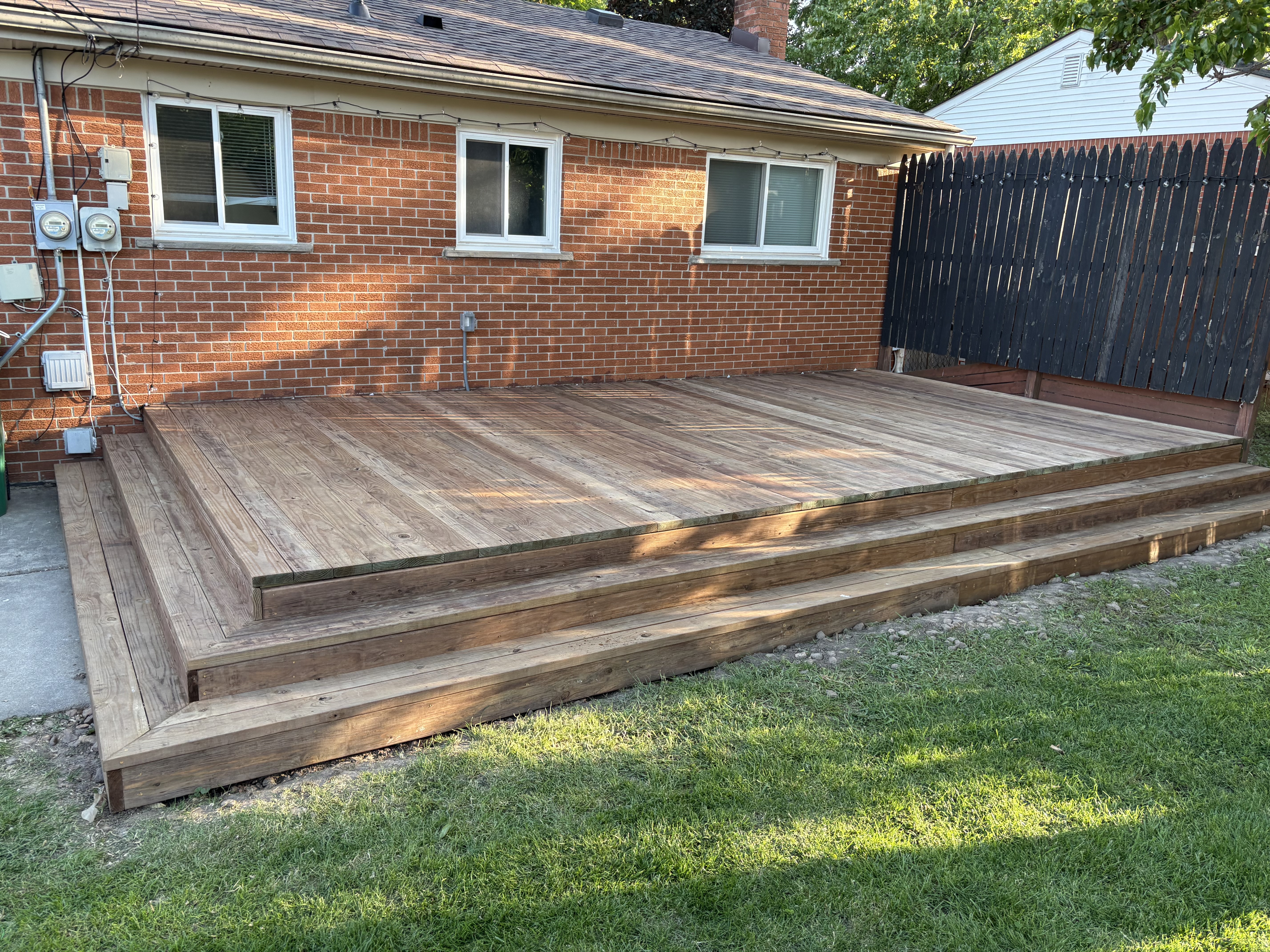 Backyard deck built with pressure-treated wood, horizontal platform steps, and functional layout for outdoor space expansion.